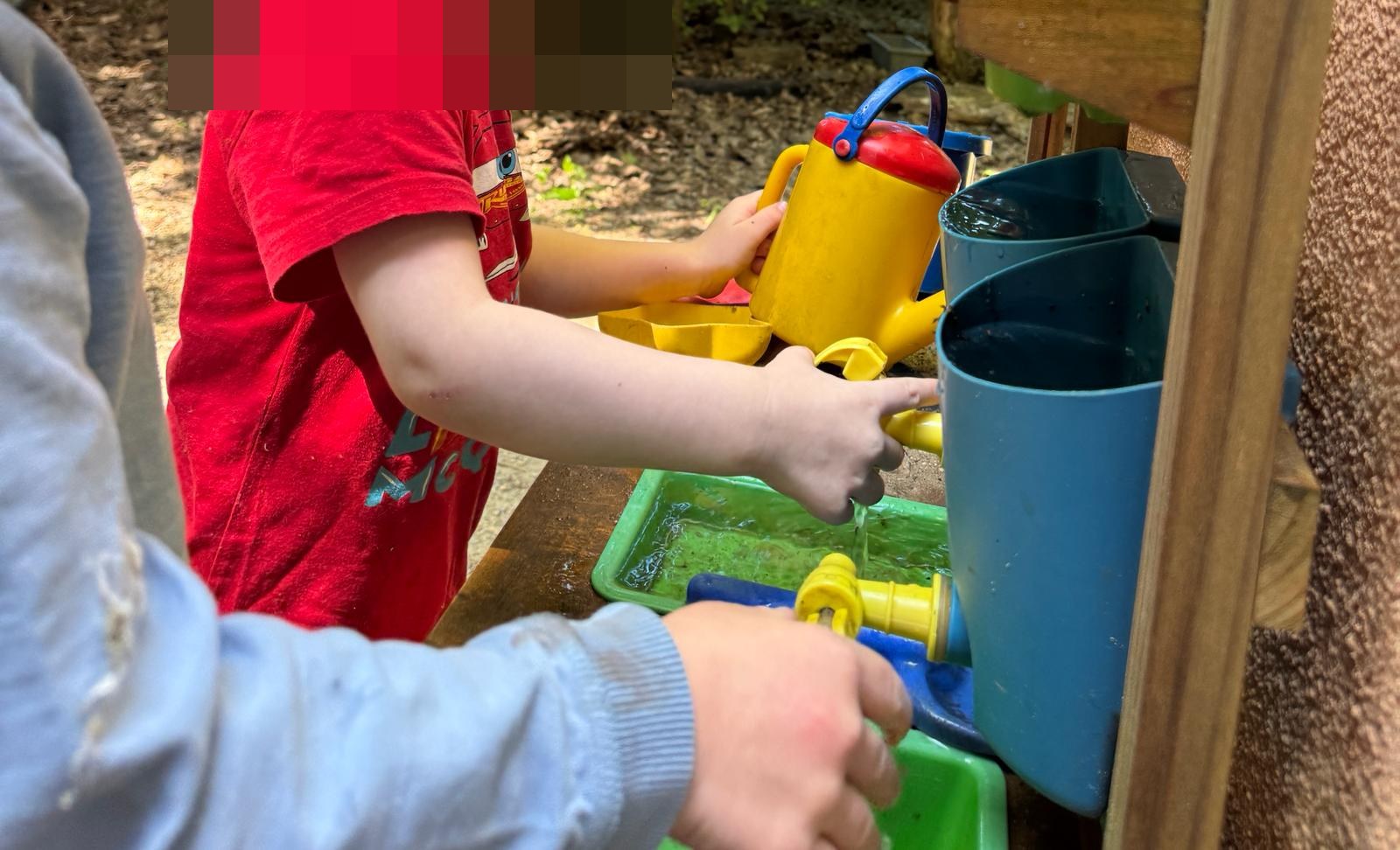 Zwei Kinder pumpen und gießen Wasser an der Matschküche