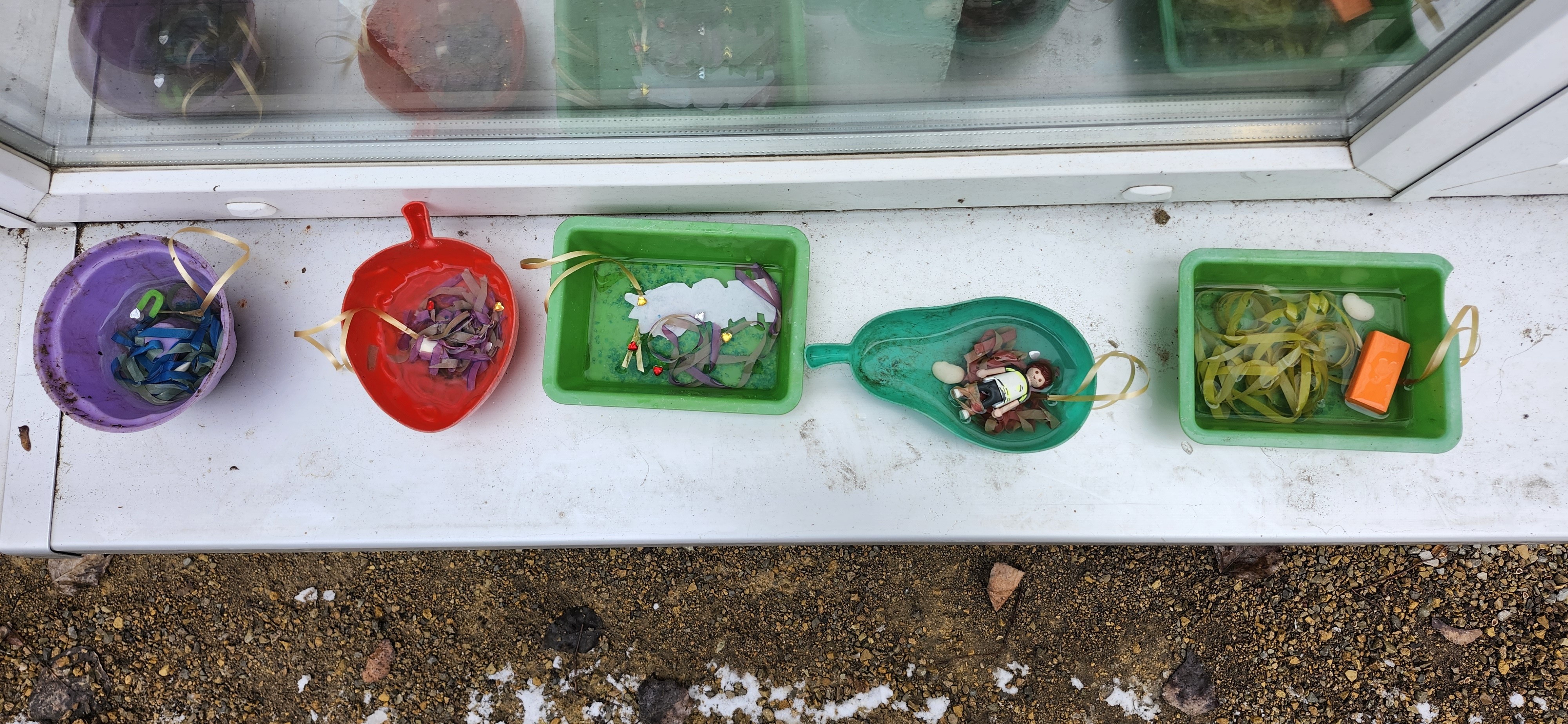 Bunte Schalen mit Bändern und Figuren gefrieren draußen