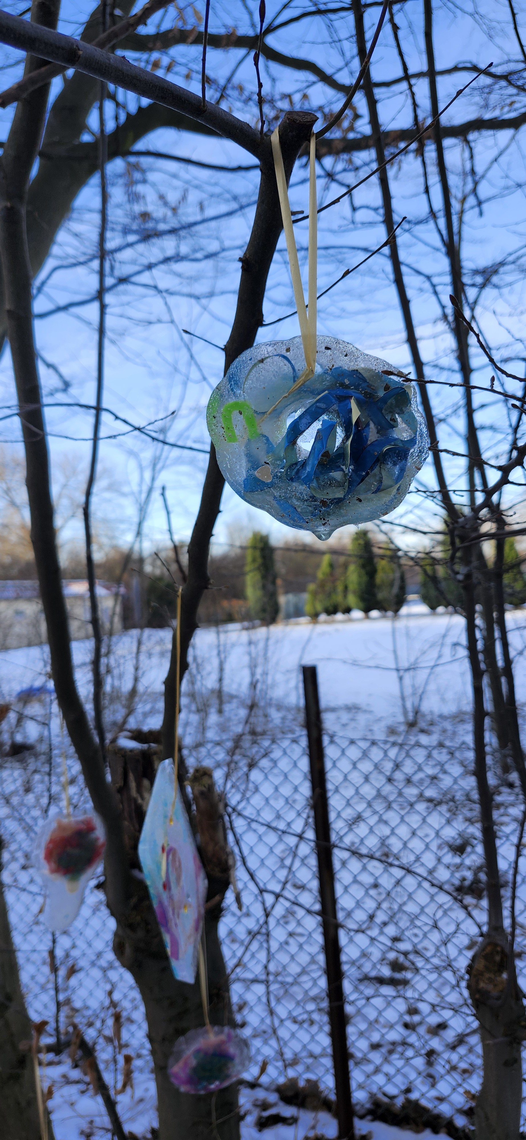 Fertiger Eis-Anhänger mit blauen Bändern hängt im Baum